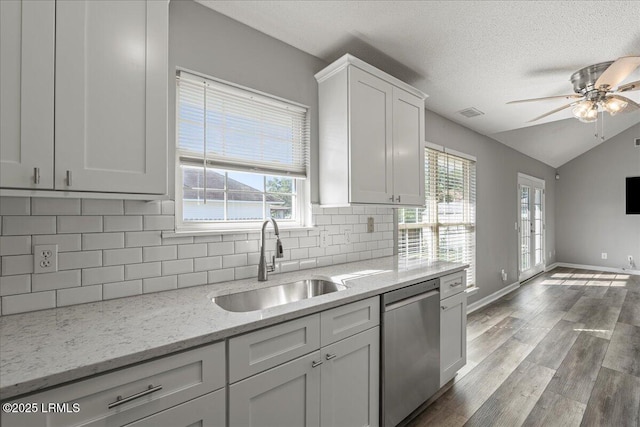 kitchen featuring stainless steel dishwasher, a sink, a ceiling fan, tasteful backsplash, and lofted ceiling