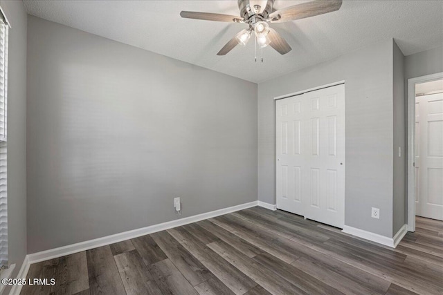 unfurnished bedroom with dark wood-style floors, a closet, baseboards, a textured ceiling, and ceiling fan