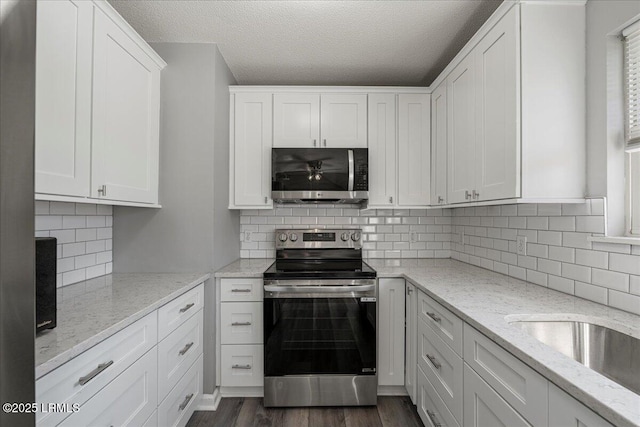 kitchen featuring stainless steel appliances, a textured ceiling, white cabinets, dark wood-style floors, and decorative backsplash