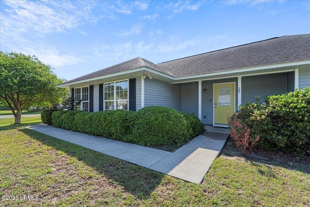 entrance to property with a yard and a shingled roof