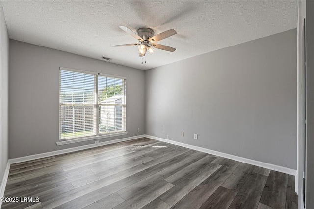 empty room featuring a ceiling fan, dark wood finished floors, a textured ceiling, and baseboards