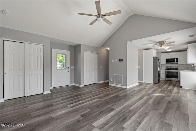 unfurnished living room featuring ceiling fan, a sink, high vaulted ceiling, and dark wood-type flooring
