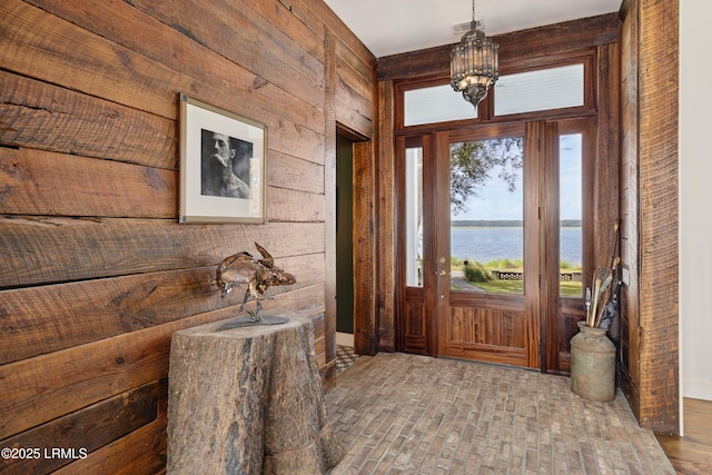70 Brams Point Rd, Hilton Head Island, SC 29926 - entrance foyer featuring wooden walls, a water view, brick patterned floors, and a chandelier