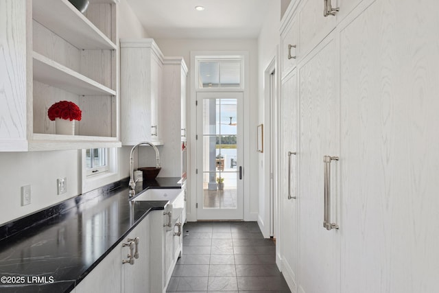 70 Brams Point Rd, Hilton Head Island, SC 29926 - kitchen with a sink, open shelves, white cabinets, dark countertops, and dark tile patterned floors