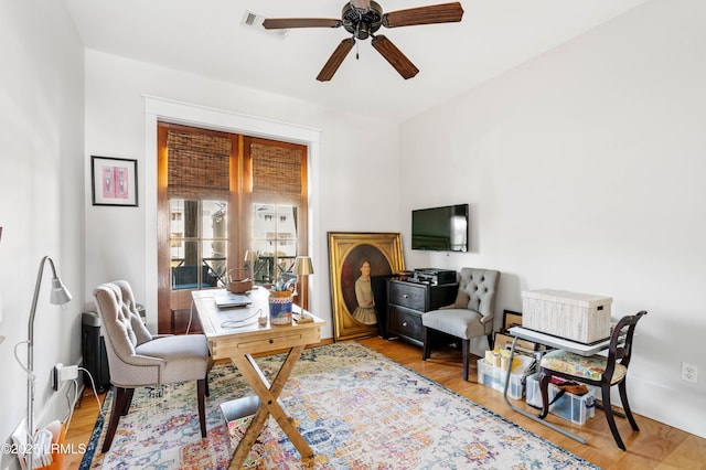 home office with light wood-type flooring and a ceiling fan