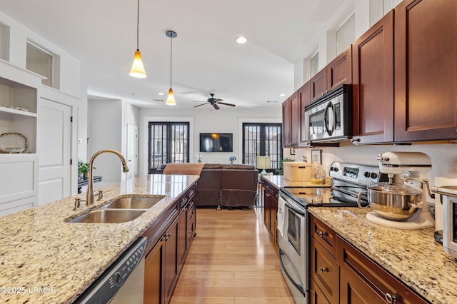 kitchen featuring a sink, french doors, appliances with stainless steel finishes, light wood-type flooring, and pendant lighting