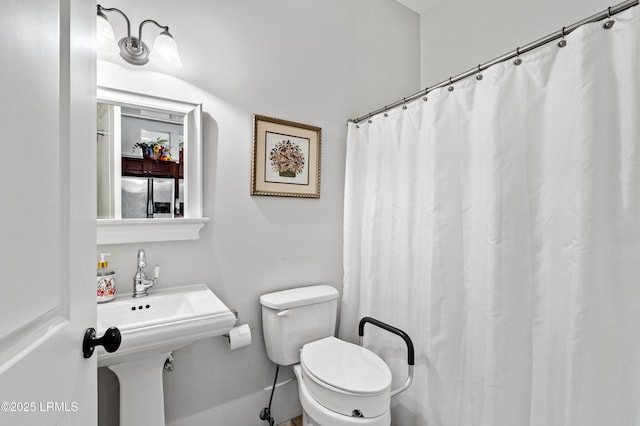 full bath featuring toilet, curtained shower, and a sink