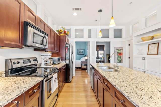 kitchen featuring light stone counters, decorative light fixtures, visible vents, appliances with stainless steel finishes, and a sink