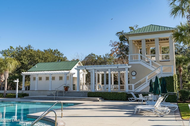 rear view of property with metal roof, a patio, a community pool, and a pergola