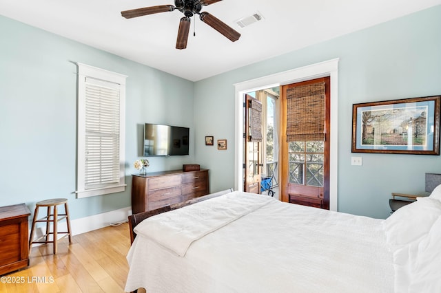 bedroom with ceiling fan, wood finished floors, visible vents, baseboards, and access to outside