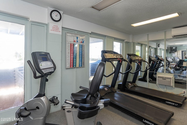 workout area with a textured ceiling and a wall mounted AC