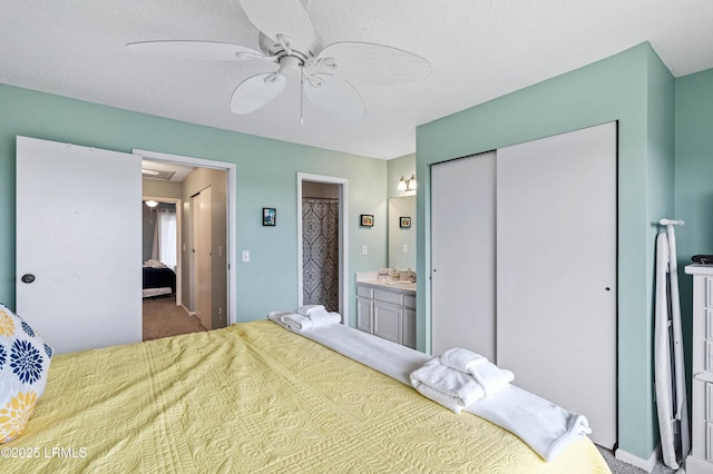 bedroom with carpet floors, a closet, ensuite bathroom, ceiling fan, and a sink