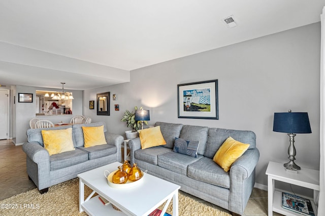 living room featuring an inviting chandelier, light tile patterned floors, baseboards, and visible vents