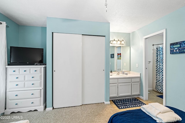 interior space featuring connected bathroom, a sink, a textured ceiling, baseboards, and a closet