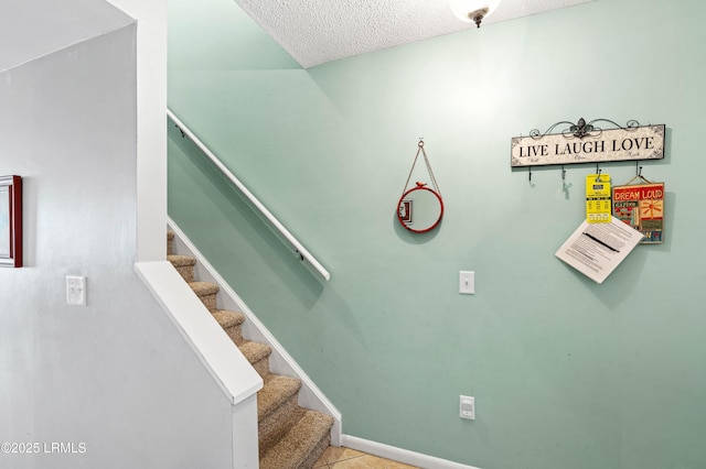 staircase with baseboards, a textured ceiling, and tile patterned floors