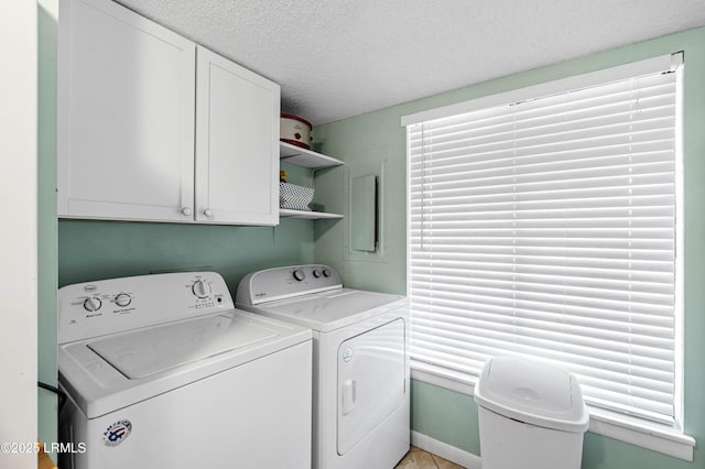laundry room with washer and dryer, a textured ceiling, and cabinet space