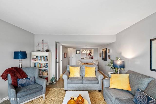 tiled living room with baseboards and a notable chandelier