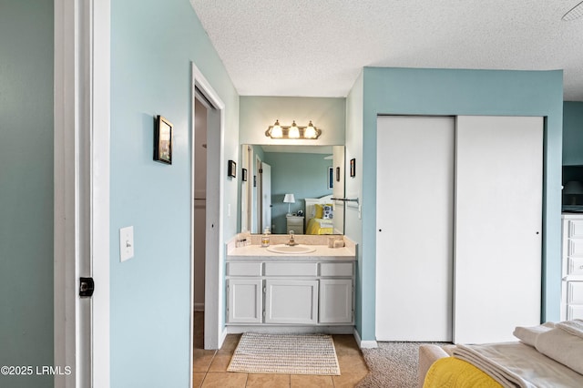 ensuite bathroom featuring vanity, tile patterned flooring, ensuite bathroom, and a textured ceiling