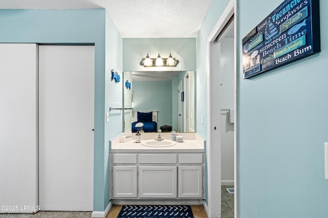 bathroom with baseboards, a textured ceiling, connected bathroom, and vanity