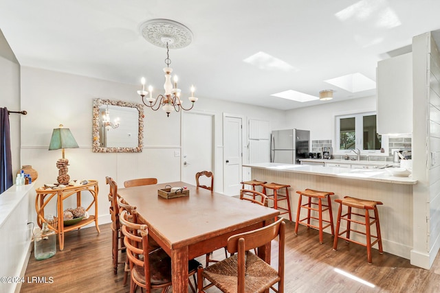 dining area featuring an inviting chandelier, a skylight, and wood-type flooring