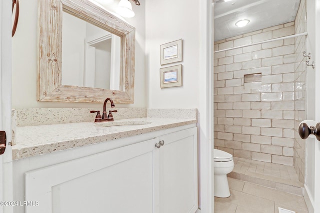 bathroom featuring vanity, tiled shower, tile patterned floors, and toilet