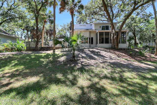 back of house with a wooden deck, a sunroom, and a lawn