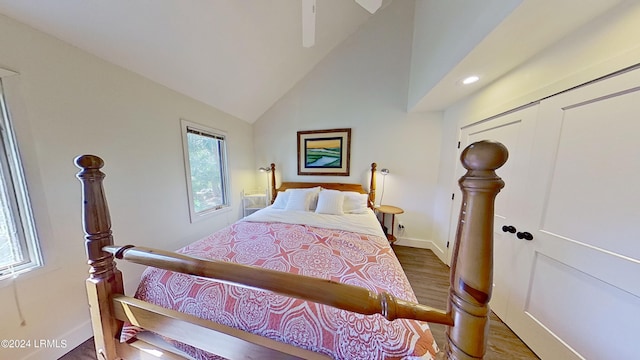 bedroom with multiple windows, hardwood / wood-style floors, vaulted ceiling, and a closet