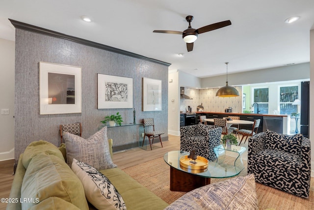 living room featuring ornamental molding, sink, ceiling fan, and light hardwood / wood-style flooring