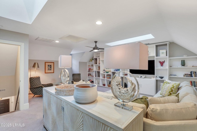 carpeted living room with ceiling fan and vaulted ceiling with skylight