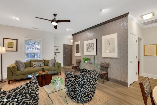 living room with ornamental molding, ceiling fan, and light wood-type flooring