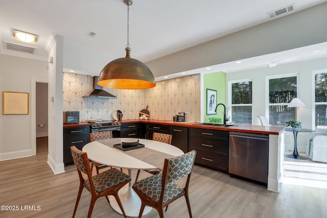 kitchen with sink, backsplash, stainless steel appliances, decorative light fixtures, and wall chimney exhaust hood