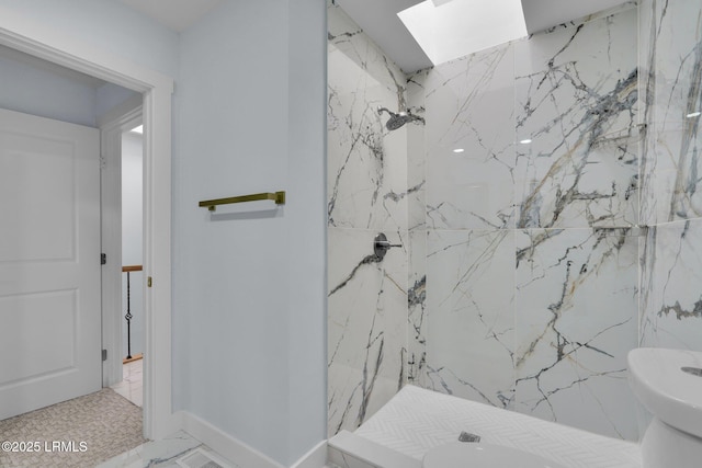 full bath featuring a skylight, marble finish floor, a marble finish shower, toilet, and baseboards