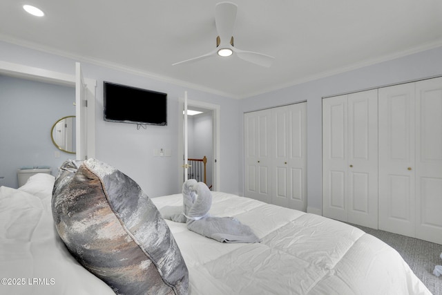 bedroom featuring crown molding, a ceiling fan, two closets, and carpet flooring