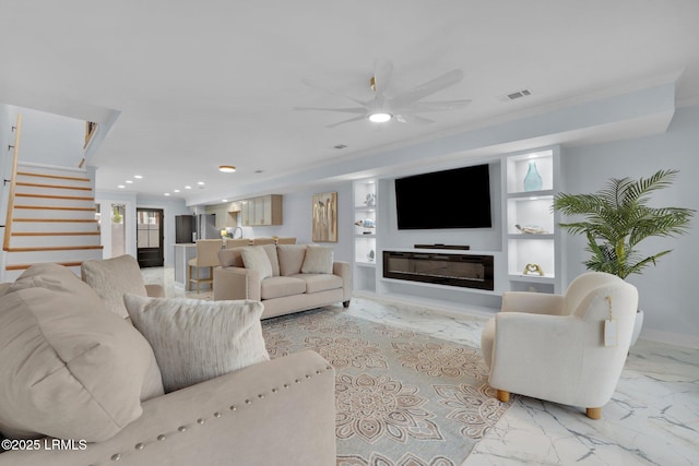 living room with stairs, marble finish floor, a glass covered fireplace, and built in features