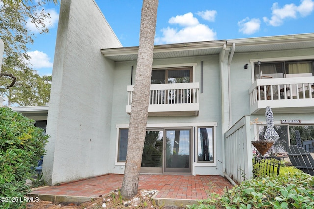 rear view of house featuring a patio and stucco siding