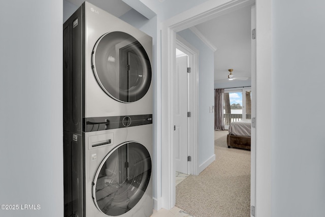 clothes washing area featuring stacked washer and dryer, baseboards, laundry area, and carpet flooring