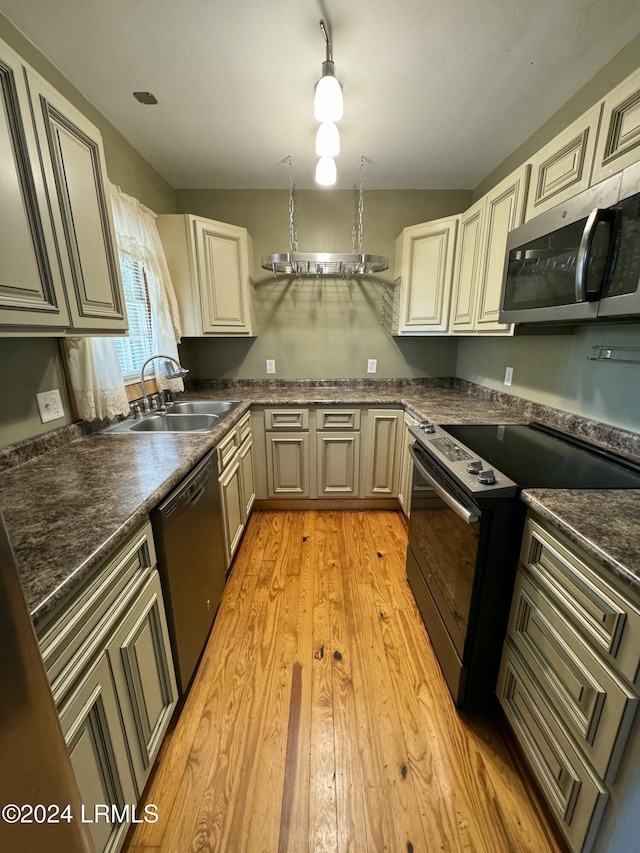 kitchen with sink, dishwasher, electric stove, light hardwood / wood-style floors, and cream cabinetry