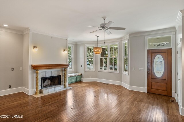 unfurnished living room featuring a fireplace, wood-type flooring, ornamental molding, and ceiling fan