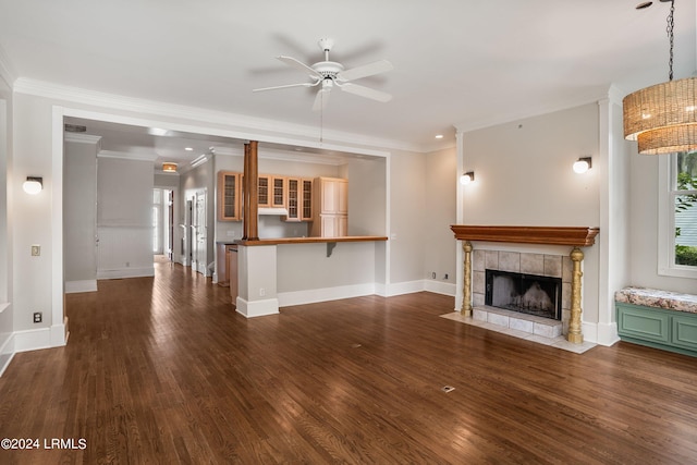 unfurnished living room with a tiled fireplace, crown molding, ceiling fan, and dark hardwood / wood-style flooring