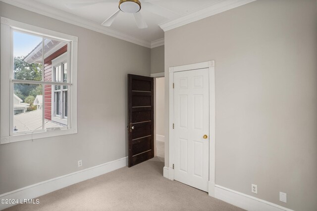 unfurnished bedroom with crown molding, light colored carpet, and ceiling fan