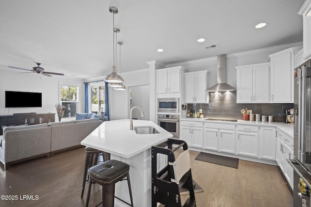 kitchen featuring tasteful backsplash, visible vents, appliances with stainless steel finishes, a sink, and wall chimney exhaust hood