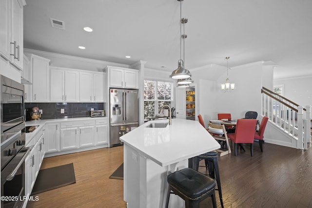 kitchen with visible vents, appliances with stainless steel finishes, a sink, and wood finished floors