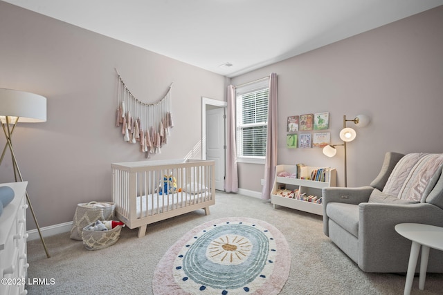 bedroom featuring a nursery area, baseboards, and carpet