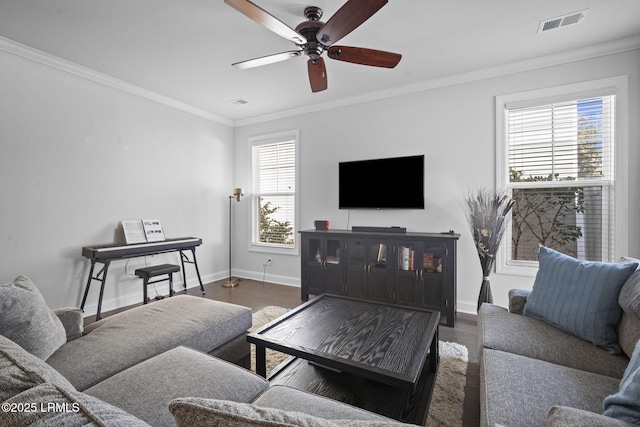 living room featuring visible vents, crown molding, baseboards, and wood finished floors