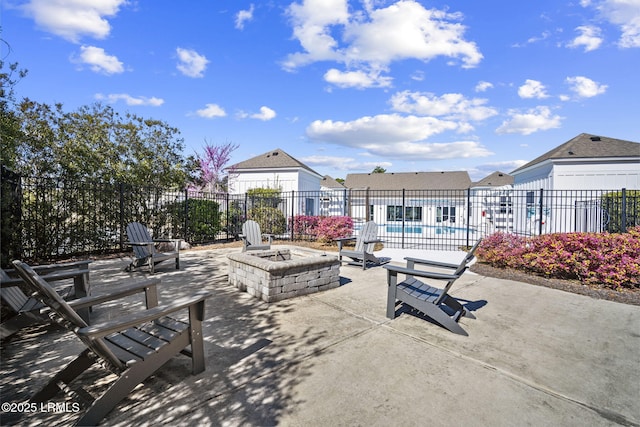 view of patio featuring an outdoor fire pit, fence, and a community pool