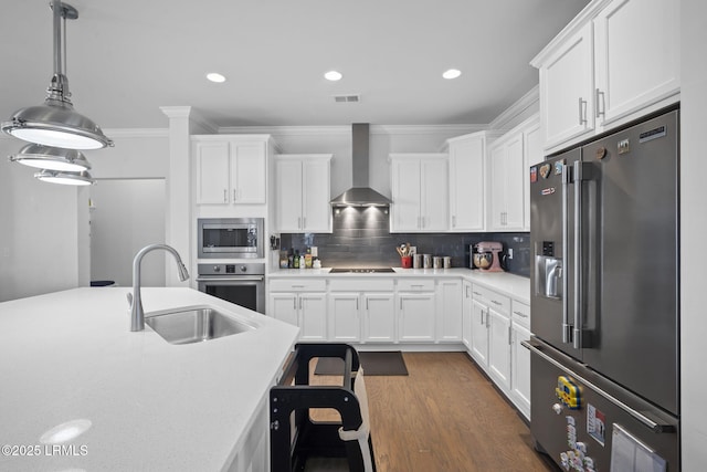 kitchen with a sink, light countertops, appliances with stainless steel finishes, wall chimney range hood, and decorative backsplash