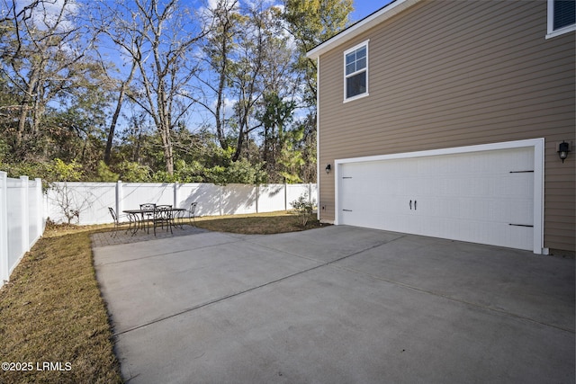 exterior space featuring a patio, concrete driveway, an attached garage, and fence