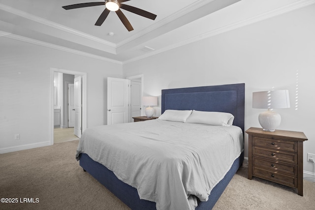 bedroom featuring a tray ceiling, carpet, crown molding, ensuite bathroom, and baseboards