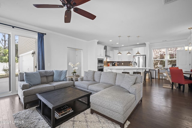 living area with ornamental molding, recessed lighting, ceiling fan with notable chandelier, and dark wood-style floors