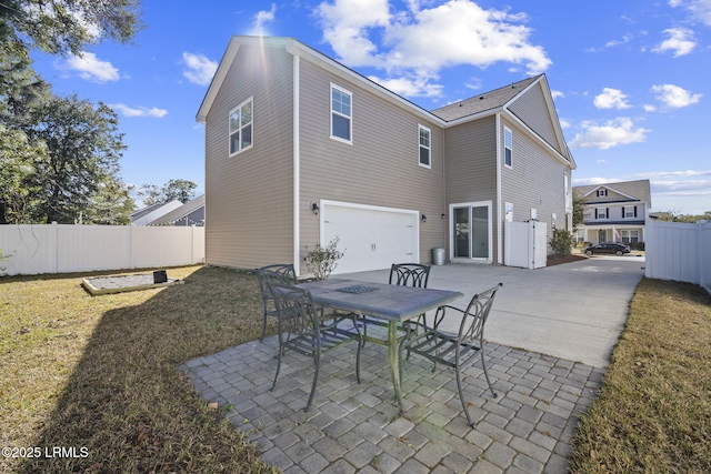 rear view of property with a patio, outdoor dining area, a garage, fence, and concrete driveway